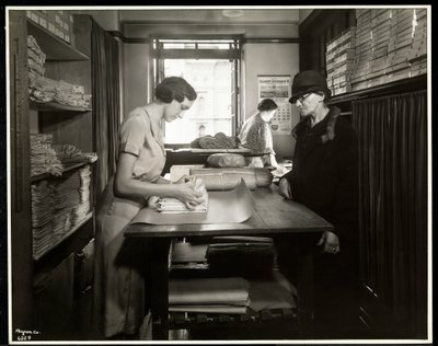 Junge Frau, die Stoffmaterialien für eine Heimarbeiterin einpackt, bei der New York Association for the Blind, 111 East 59th Street, New York, 1931 von Byron Company